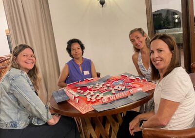 Four women sitting around a round table playing a board game.